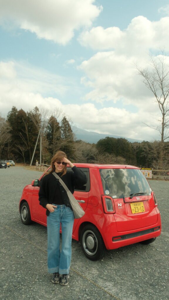 Woman standing in front of a car in front of Mount Fuji, Japan