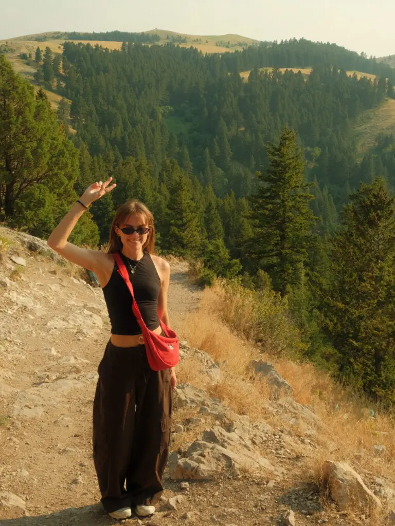 Woman hiking the Drinking Horse Trail in Bozeman, Montana, with forested hills in the background