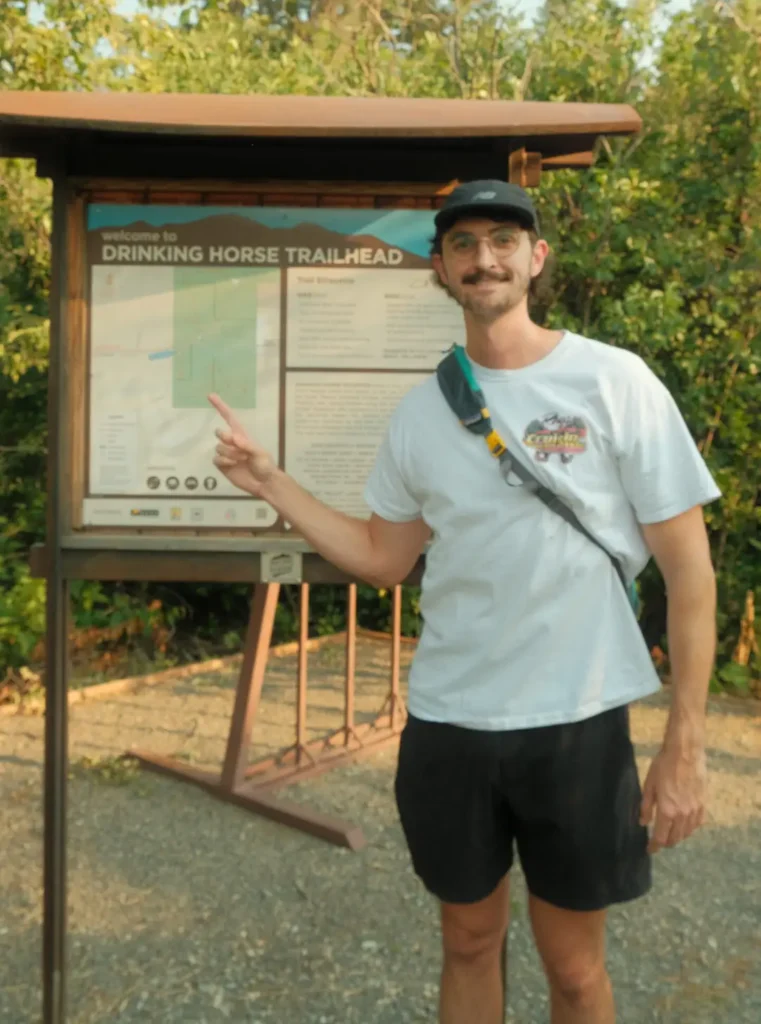 Man pointing at the Drinking Horse Trailhead sign in Bozeman, Montana